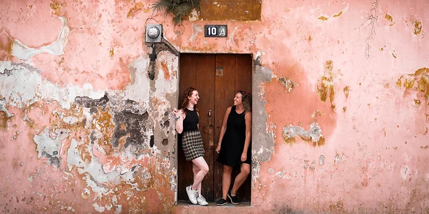 To kvinner står foran en fargerik mur i Antigua i Guatemala
