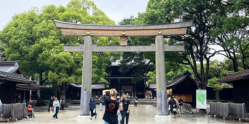 Kvinne tar bilde av et par under en Torii-port ved Meiji-helligdommen