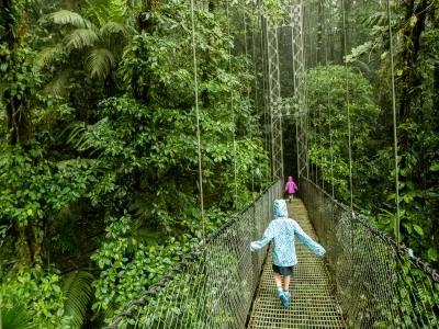 Barn går over en hengebro i Costa Rica i regnvær