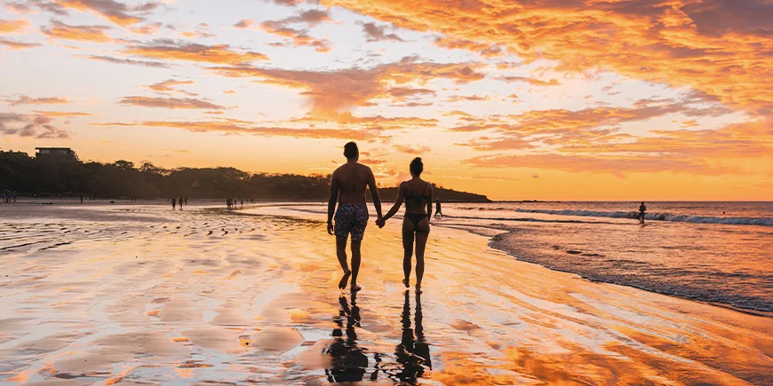 Mann og kvinne går på Tamarindo Beach i Costa Rica