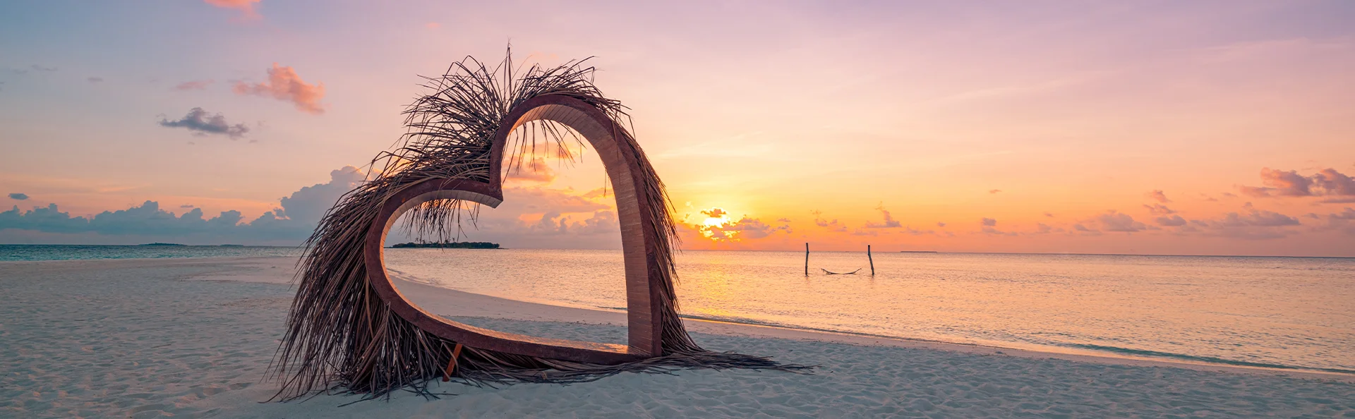 Skulptur av et hjerte på en tropisk strand i solnedgang