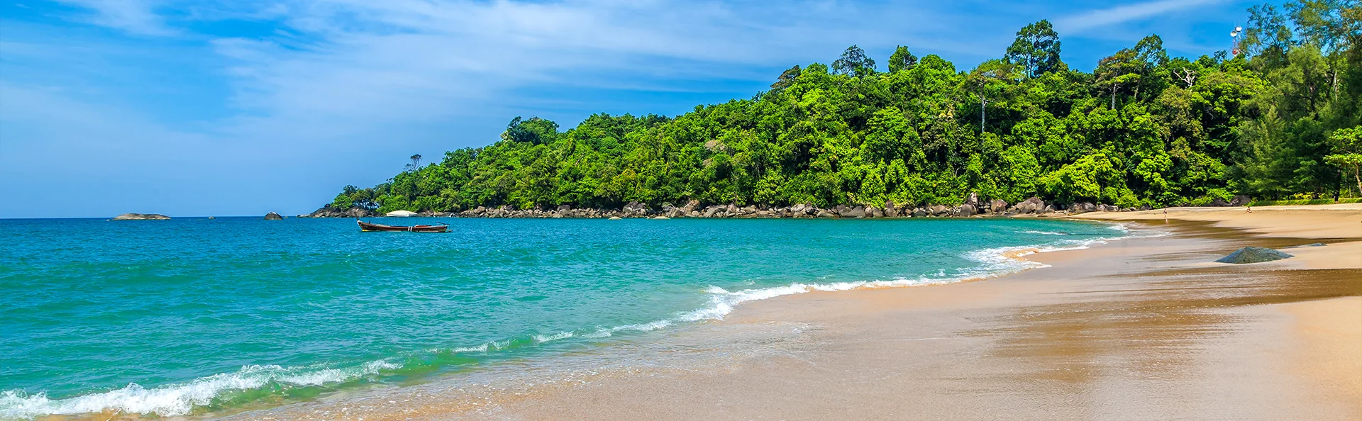 Tropisk strand i Thailand med turkisblått hav, myk sand og grønn jungel i bakgrunnen.