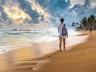 En kvinne går på stranden på Sri Lanka